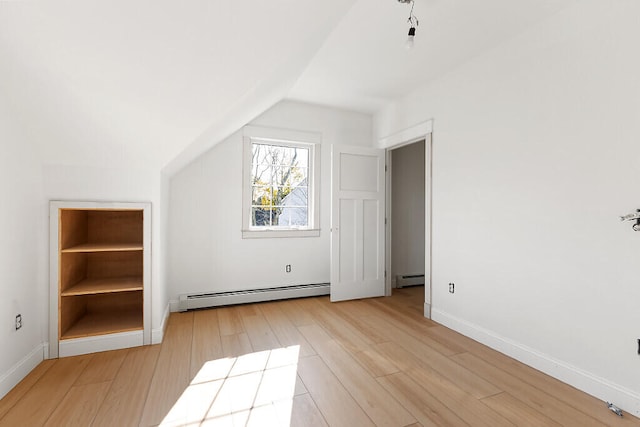 additional living space featuring a baseboard radiator, lofted ceiling, and light hardwood / wood-style floors