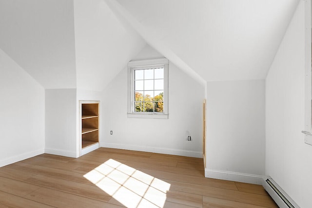 additional living space with baseboard heating, light wood-type flooring, and vaulted ceiling