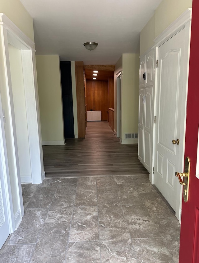 corridor with dark hardwood / wood-style floors and wood walls