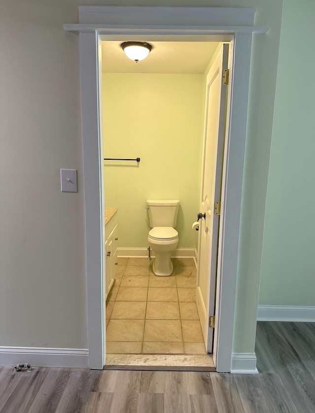 bathroom featuring toilet, vanity, and wood-type flooring