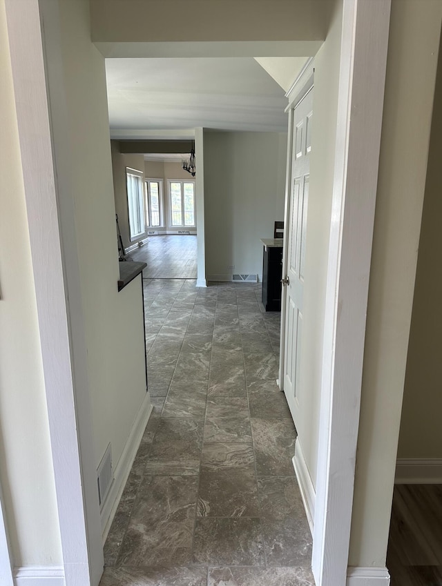 hallway featuring dark tile floors and an inviting chandelier