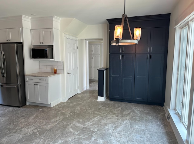 kitchen featuring appliances with stainless steel finishes, hanging light fixtures, an inviting chandelier, backsplash, and light tile floors