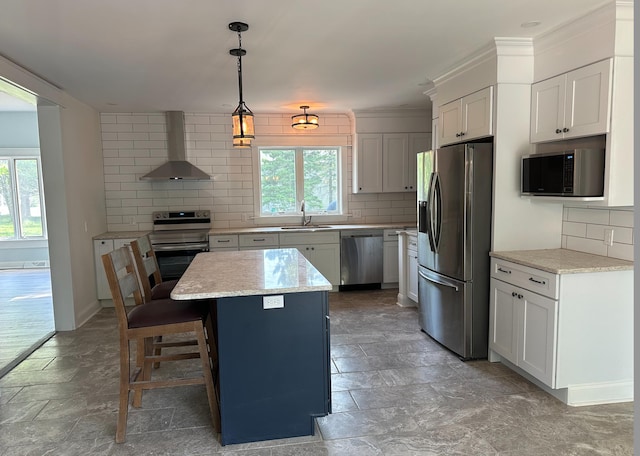 kitchen with plenty of natural light, a kitchen bar, stainless steel appliances, and wall chimney exhaust hood