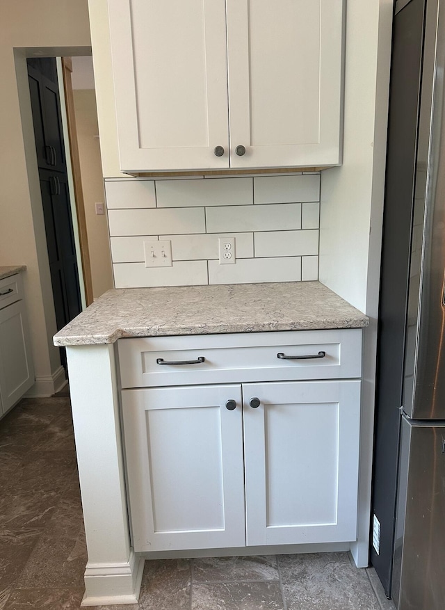 kitchen featuring tasteful backsplash, white cabinetry, and refrigerator