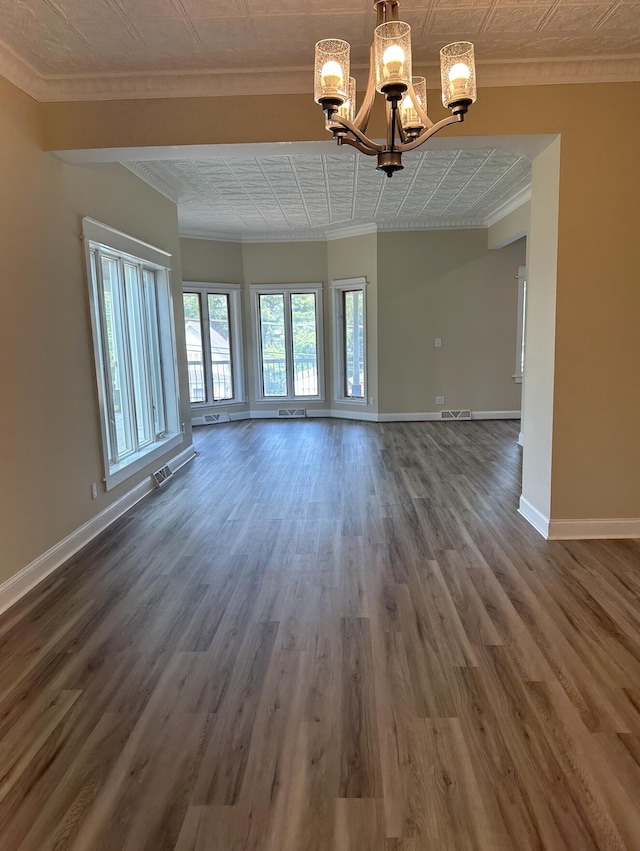 spare room featuring a notable chandelier, crown molding, and dark hardwood / wood-style flooring