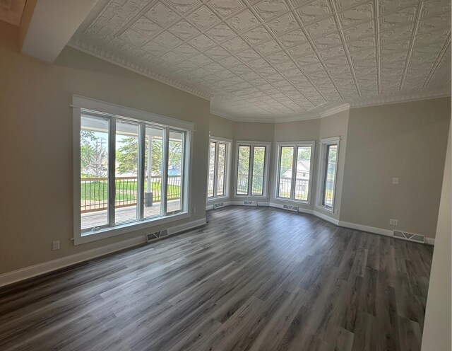 empty room with crown molding, dark wood-type flooring, and plenty of natural light