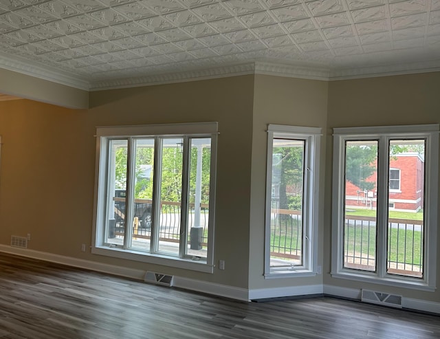 spare room featuring a healthy amount of sunlight, ornamental molding, and dark wood-type flooring