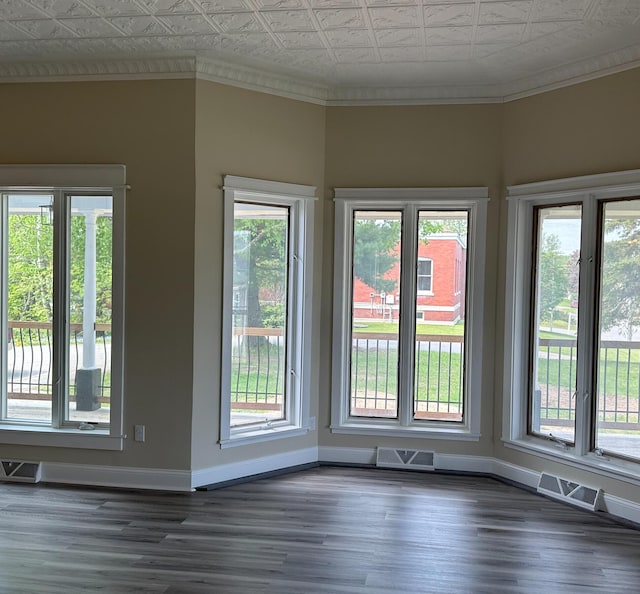 interior space featuring dark wood-type flooring, ornamental molding, and a healthy amount of sunlight