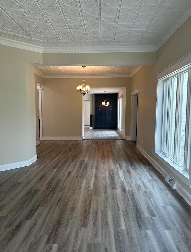 unfurnished living room with a notable chandelier, ornamental molding, and dark wood-type flooring