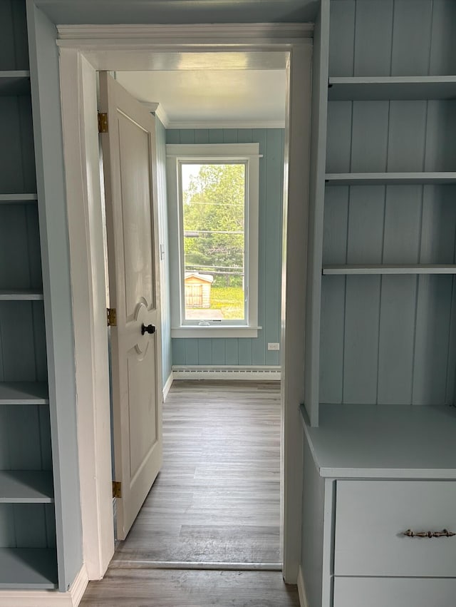 doorway featuring a baseboard radiator, light wood-type flooring, and crown molding