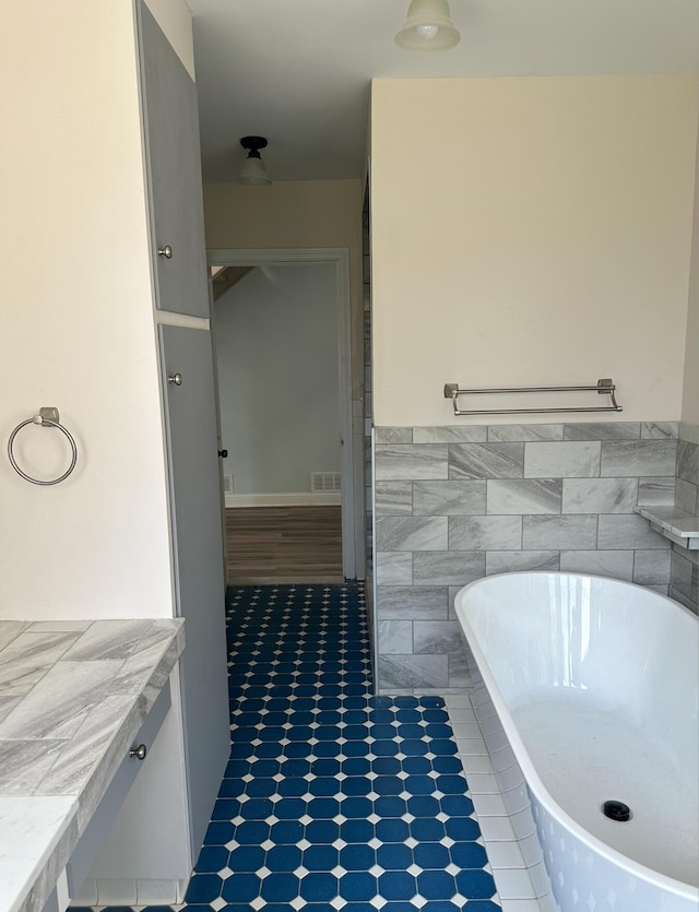 bathroom with tile floors, a bathing tub, and vanity