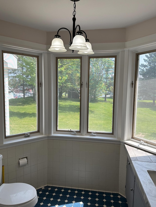 unfurnished dining area featuring tile walls, a wealth of natural light, and a chandelier