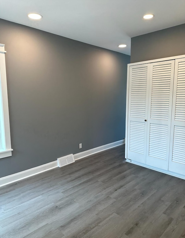 unfurnished bedroom featuring a closet and dark wood-type flooring