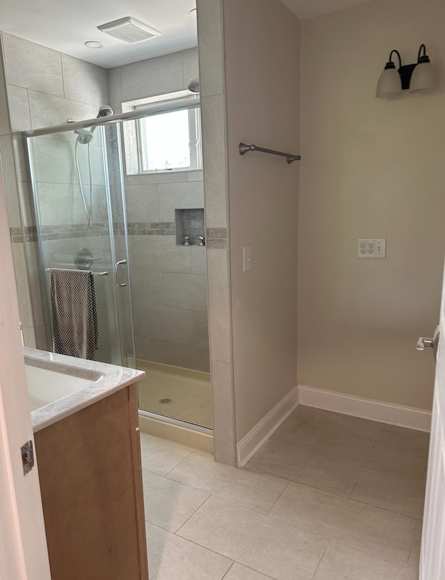 bathroom featuring tile floors, vanity, and a shower with shower door