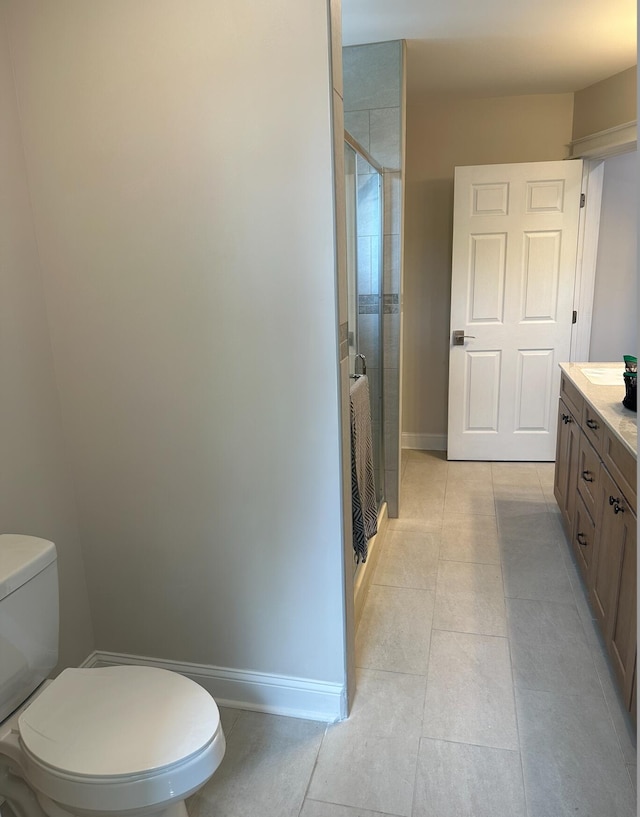 bathroom featuring toilet, vanity, a shower with door, and tile flooring