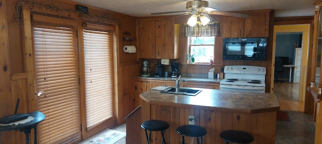 kitchen featuring wood walls, ceiling fan, white electric range oven, and sink