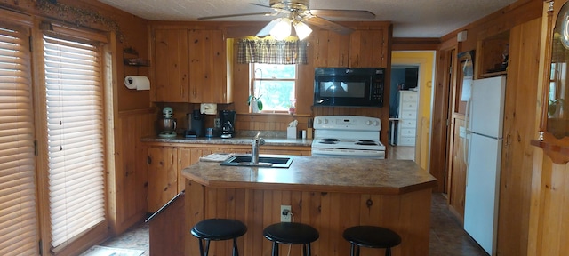 kitchen with a kitchen breakfast bar, ceiling fan, white appliances, dark tile flooring, and sink