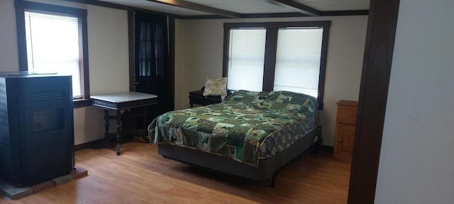 bedroom with multiple windows, beam ceiling, and wood-type flooring