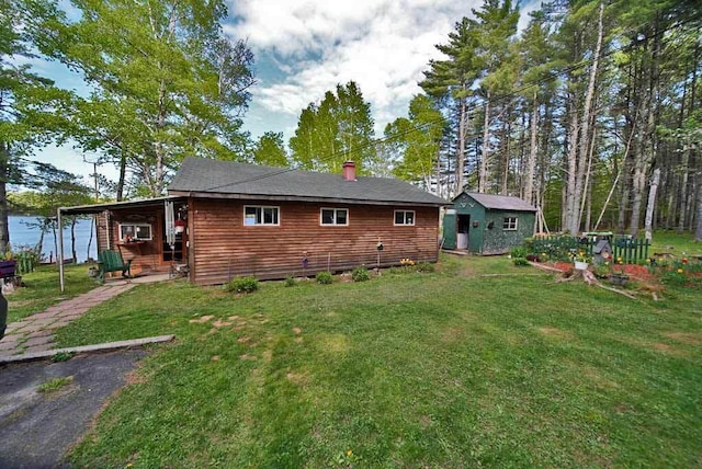 rear view of property featuring a yard and an outdoor structure