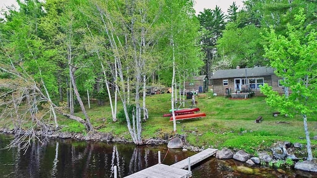 view of dock with a lawn and a water view