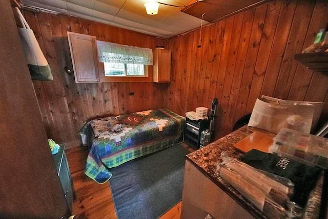 bedroom with wooden walls and hardwood / wood-style flooring