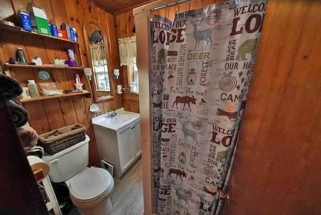 bathroom featuring wooden walls, vanity with extensive cabinet space, toilet, and hardwood / wood-style flooring