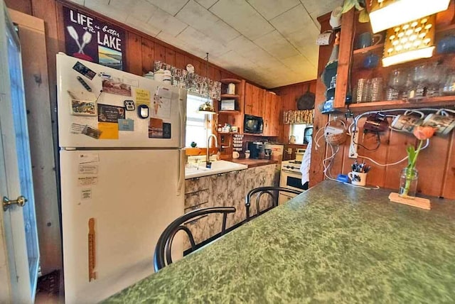 interior space featuring sink, white appliances, and wood walls