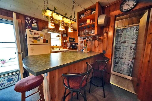 bar featuring wooden walls, white refrigerator, dark carpet, and sink