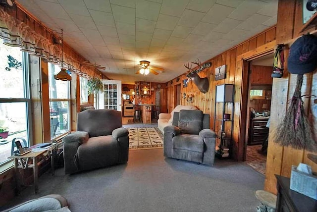 living room with wooden walls, ceiling fan, and a wealth of natural light