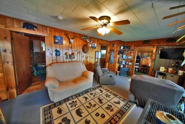 carpeted living room featuring wood walls and ceiling fan