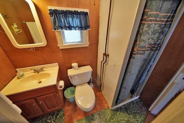 bathroom featuring wood walls, toilet, and vanity