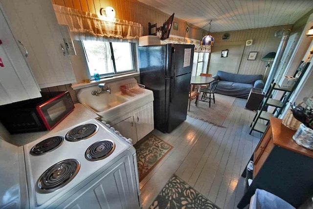 kitchen with white cabinets, light wood-type flooring, black appliances, and sink