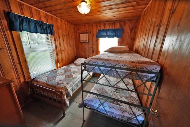 bedroom featuring wooden walls, wooden ceiling, and multiple windows