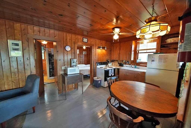 dining room with wooden ceiling, ceiling fan, sink, and wooden walls