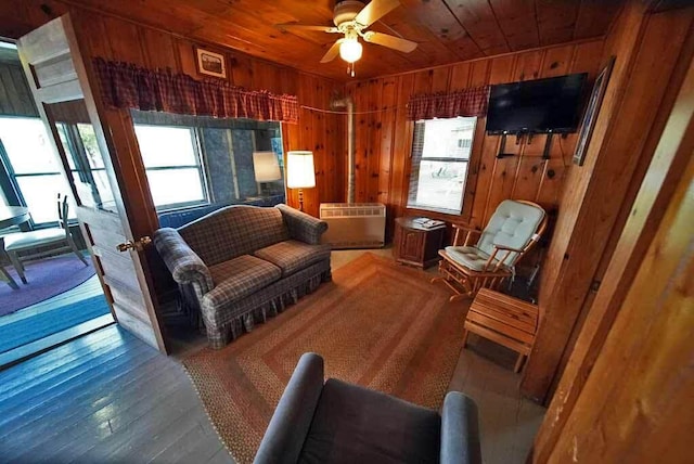 living room featuring wooden walls, ceiling fan, and a wealth of natural light