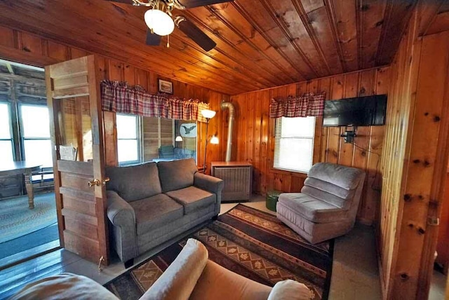 living room featuring ceiling fan, wood walls, and wood ceiling