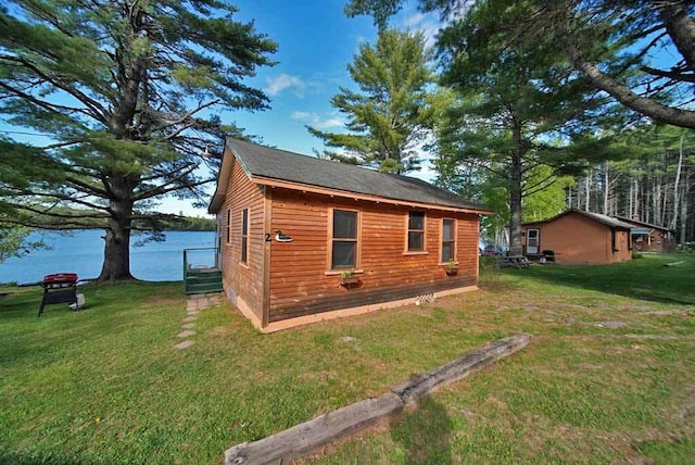 rear view of property featuring a water view and a lawn