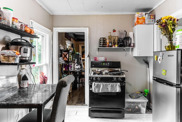 kitchen featuring light wood-type flooring, black gas range, and stainless steel refrigerator