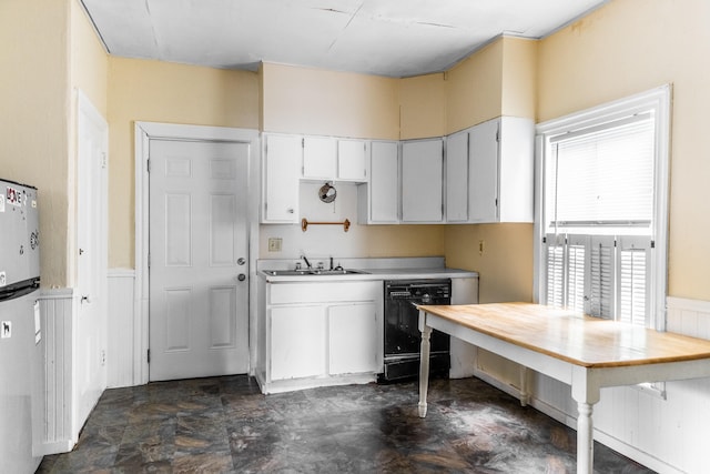 kitchen with black dishwasher, sink, white refrigerator, and white cabinets