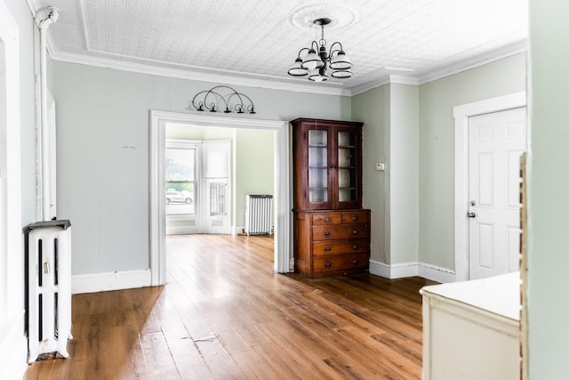 interior space with crown molding, radiator heating unit, wood-type flooring, and a chandelier