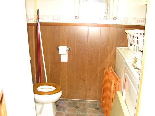 bathroom featuring tile flooring, toilet, and wooden walls