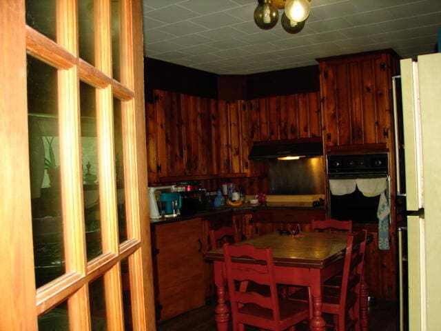 kitchen featuring a kitchen island, white fridge, black oven, and a chandelier