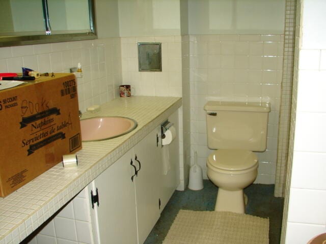 bathroom featuring backsplash, tile walls, toilet, and vanity