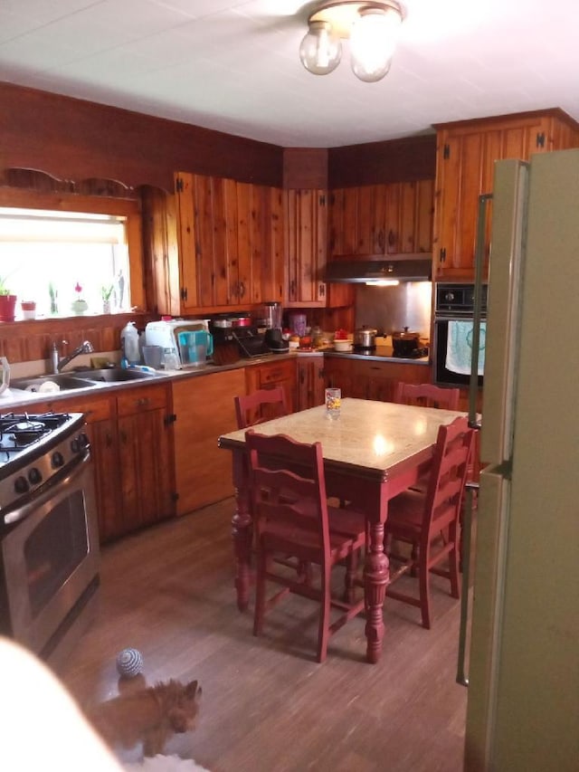 kitchen with black oven, gas stove, white refrigerator, hardwood / wood-style flooring, and a notable chandelier