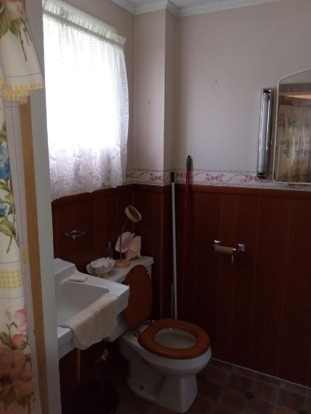 bathroom featuring tile flooring, crown molding, and toilet