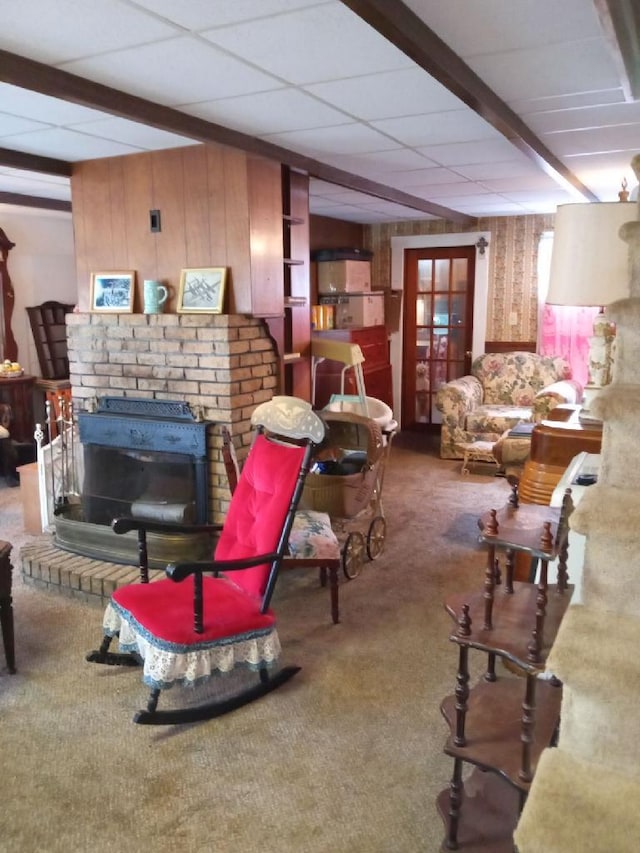 living room featuring beam ceiling, a fireplace, wood walls, and dark colored carpet