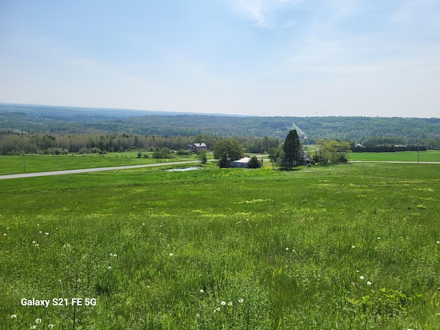 view of property's community with a rural view and a lawn