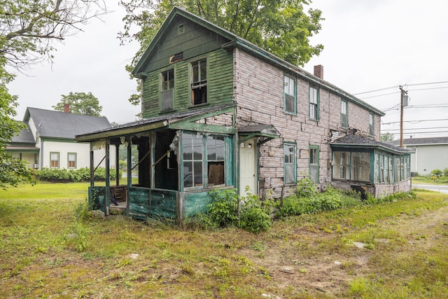 back of property with a sunroom and a lawn