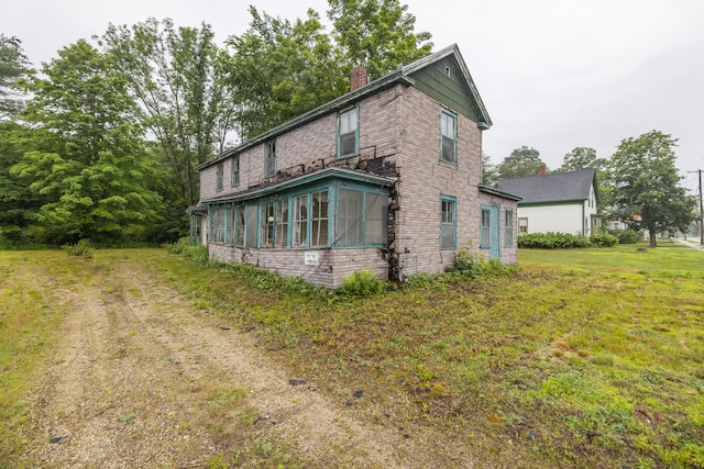view of side of property with a sunroom and a lawn