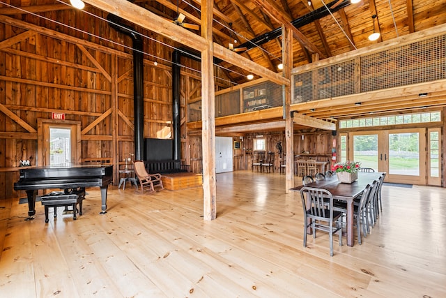 miscellaneous room featuring high vaulted ceiling, wood walls, light hardwood / wood-style floors, and french doors